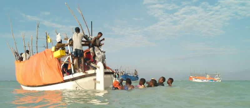 Small boat picking up refugees floating in the water